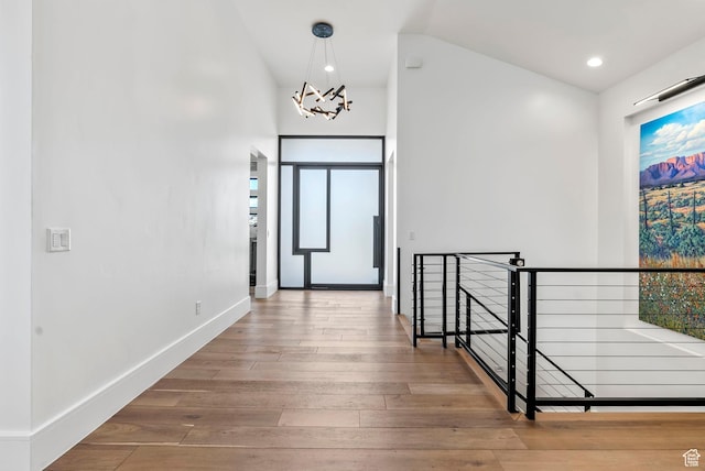 hall featuring a chandelier, hardwood / wood-style floors, and vaulted ceiling