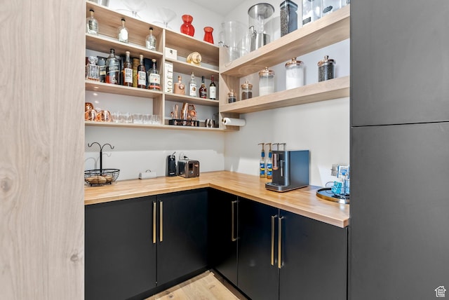 bar featuring refrigerator, light hardwood / wood-style flooring, and butcher block counters