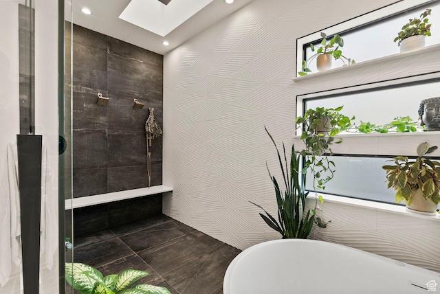 bathroom with a tub to relax in, a skylight, and tile walls