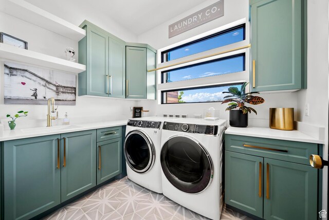 clothes washing area featuring cabinets, washing machine and dryer, and sink