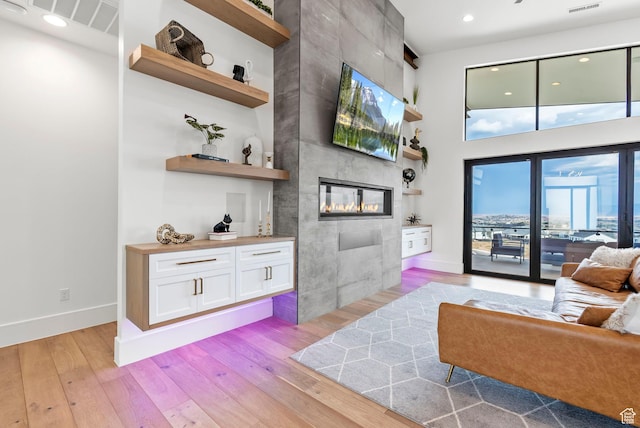 living room featuring light hardwood / wood-style flooring and a tiled fireplace