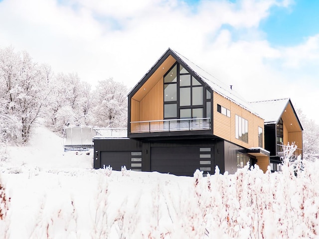 snow covered back of property featuring a garage