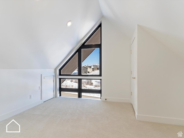 additional living space featuring light carpet and vaulted ceiling