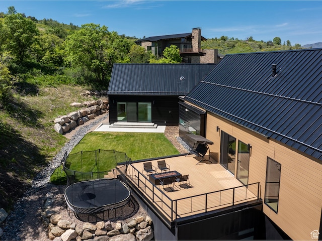 1113 S Quail Holw E, Huntsville, UT 84317 - back of house featuring a deck, a lawn, metal roof, and a trampoline
