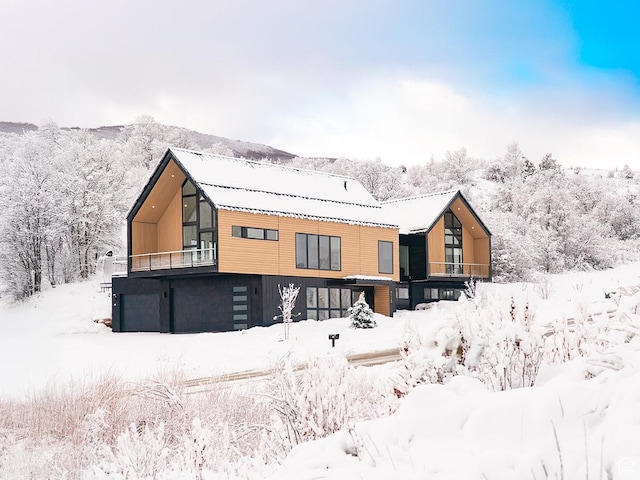 snow covered house featuring a balcony