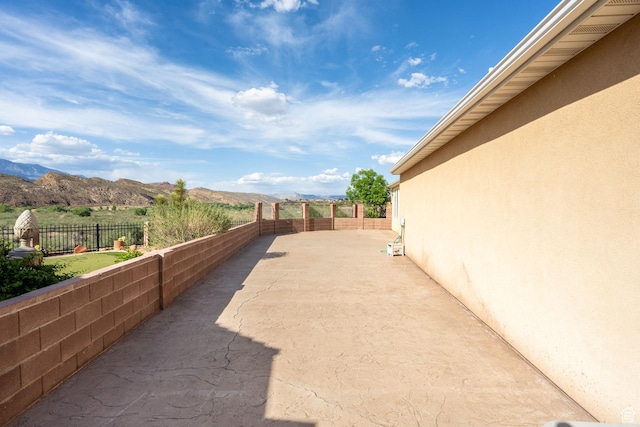 view of yard featuring a mountain view, fence, and a patio
