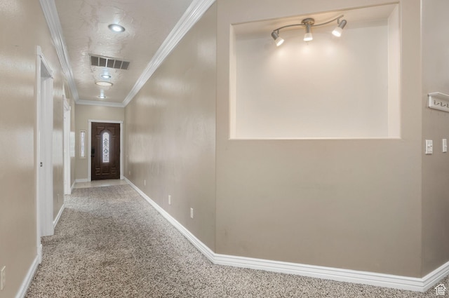hallway featuring carpet, visible vents, crown molding, and baseboards