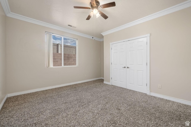 unfurnished bedroom featuring a closet, carpet, baseboards, ornamental molding, and visible vents