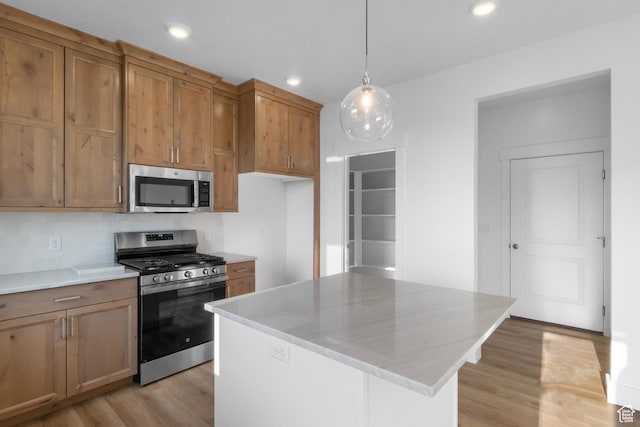 kitchen with a center island, light hardwood / wood-style floors, stainless steel appliances, and hanging light fixtures
