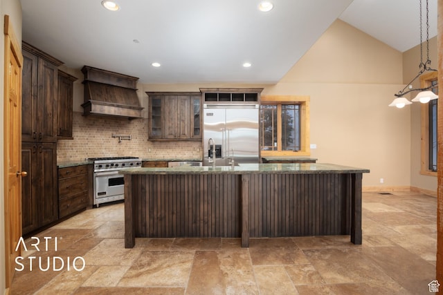 7352 Pine Dr, Park City, UT 84098 - kitchen with a kitchen island with sink, high quality appliances, decorative backsplash, dark brown cabinets, and custom range hood