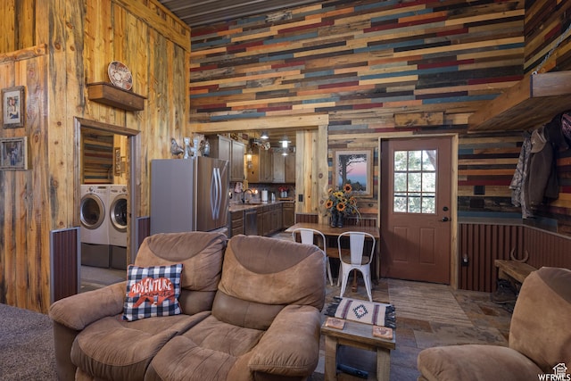 living room featuring wood walls, sink, and washing machine and clothes dryer