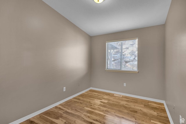 unfurnished room featuring light wood-type flooring and vaulted ceiling