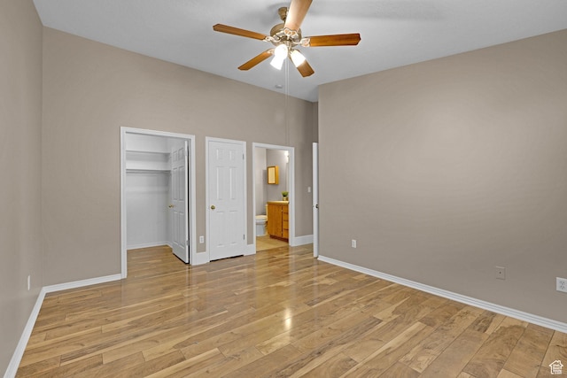 unfurnished bedroom featuring connected bathroom, ceiling fan, a walk in closet, and light wood-type flooring