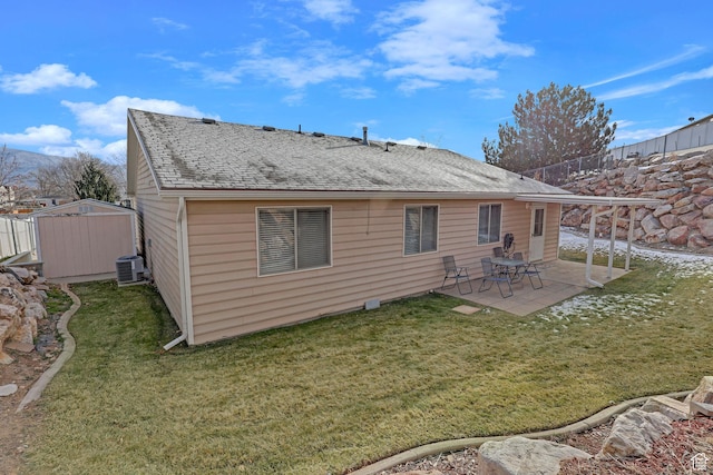 rear view of house featuring a lawn, a patio area, a storage shed, and cooling unit