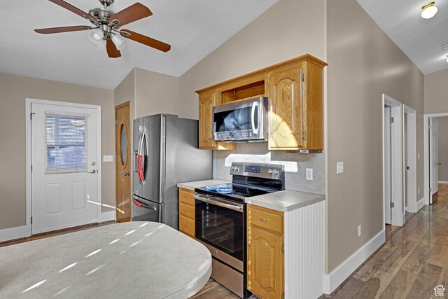 kitchen with ceiling fan, stainless steel appliances, lofted ceiling, decorative backsplash, and hardwood / wood-style flooring