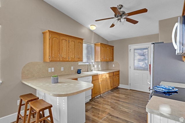 kitchen featuring white dishwasher, sink, vaulted ceiling, decorative backsplash, and kitchen peninsula