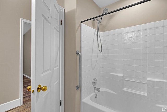 bathroom with washtub / shower combination and hardwood / wood-style flooring