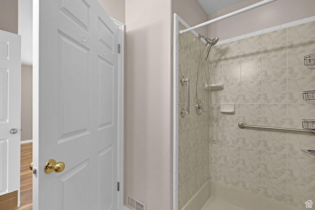 bathroom with wood-type flooring and tiled shower