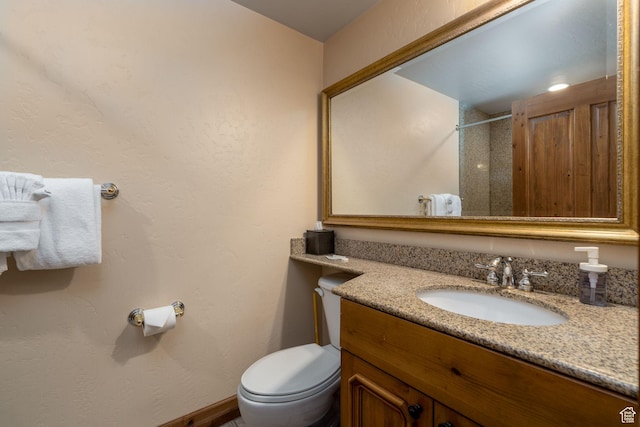 bathroom with a tile shower, vanity, and toilet