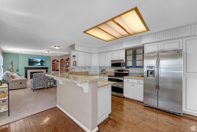 3893 S Bountiful Blvd, Bountiful, UT 84010 - kitchen with a peninsula, glass insert cabinets, a kitchen breakfast bar, white cabinetry, and stainless steel appliances