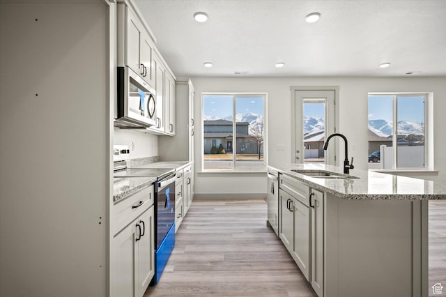 639 S 85 E Unit 28, Smithfield, UT 84335 - kitchen with baseboards, an island with sink, appliances with stainless steel finishes, light wood-style floors, and a sink
