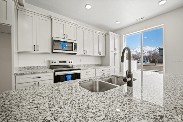 kitchen featuring visible vents, a sink, recessed lighting, stainless steel appliances, and light stone countertops