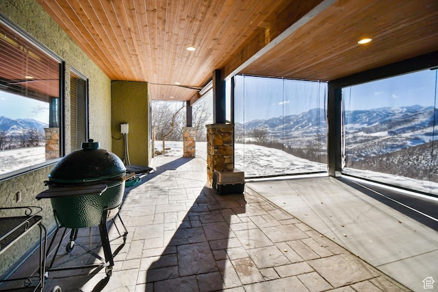 sunroom with a mountain view and wooden ceiling