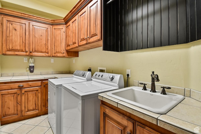 clothes washing area featuring cabinets, light tile patterned floors, sink, and washing machine and clothes dryer