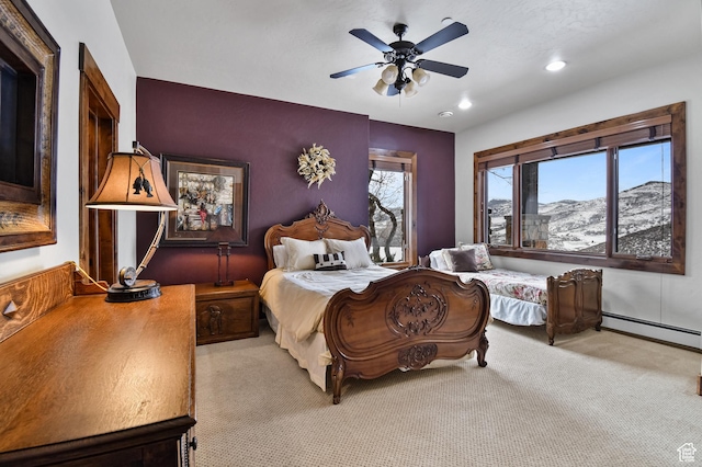 bedroom featuring light carpet, a mountain view, baseboard heating, and ceiling fan