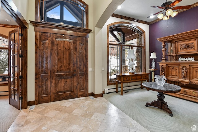 carpeted entrance foyer featuring ceiling fan, plenty of natural light, crown molding, and a baseboard heating unit