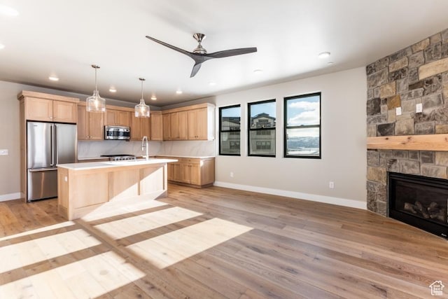 1166 W Helling Cir Unit 203, Heber City, UT 84032 - kitchen featuring a stone fireplace, an island with sink, pendant lighting, appliances with stainless steel finishes, and light wood-type flooring