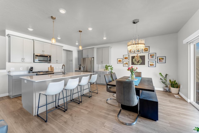 2217 E Emerald Ave, Eagle Mountain, UT 84005 - kitchen featuring appliances with stainless steel finishes, gray cabinets, a kitchen breakfast bar, an island with sink, and light countertops