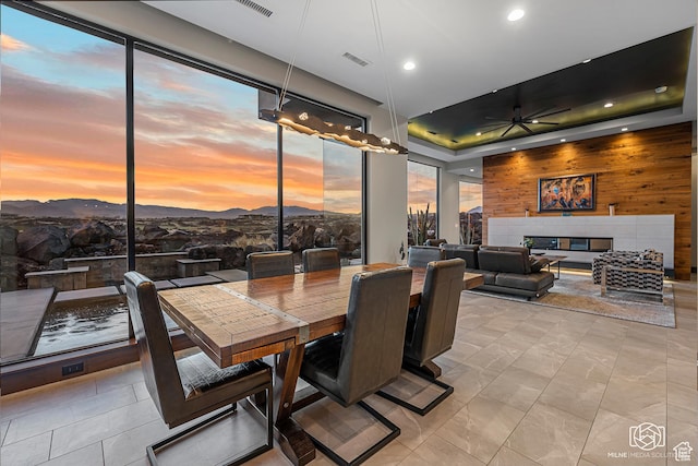 2523 N Chaco Trl, St George, UT 84770 - dining space with a ceiling fan, wood walls, a mountain view, a tiled fireplace, and a tray ceiling
