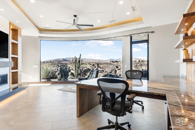 2523 N Chaco Trl, St George, UT 84770 - home office featuring a tray ceiling, a ceiling fan, a glass covered fireplace, recessed lighting, and a mountain view