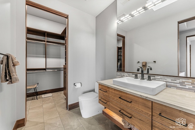 2523 N Chaco Trl, St George, UT 84770 - bathroom featuring vanity, toilet, marble look tile flooring, decorative backsplash, and baseboards