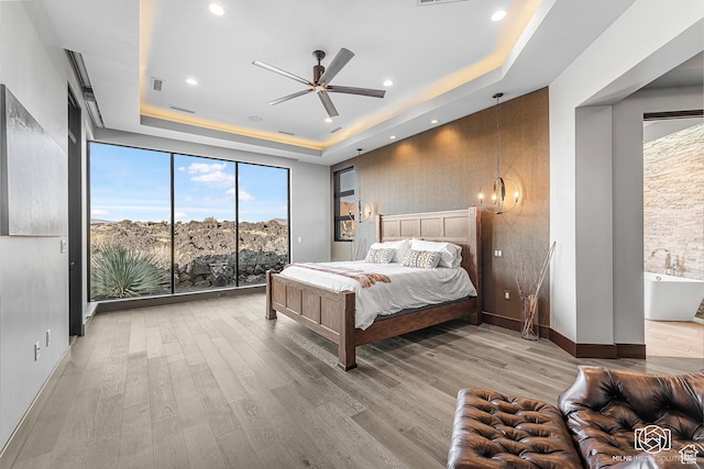 2523 N Chaco Trl, St George, UT 84770 - bedroom with a tray ceiling, wood finished floors, access to outside, a chandelier, and floor to ceiling windows
