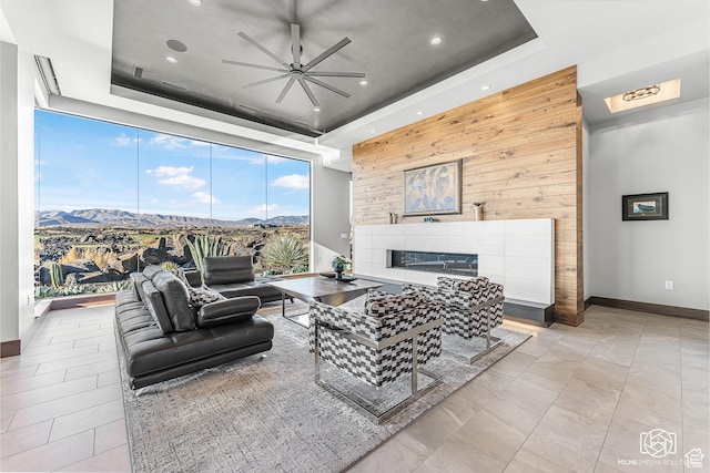 2523 N Chaco Trl, St George, UT 84770 - living room featuring a tray ceiling, a ceiling fan, a mountain view, wooden walls, and a fireplace