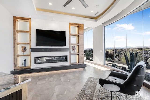 2523 N Chaco Trl, St George, UT 84770 - living area with ceiling fan, a tray ceiling, recessed lighting, built in shelves, and a glass covered fireplace