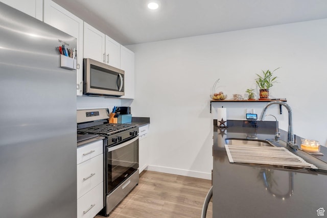 kitchen featuring white cabinets, appliances with stainless steel finishes, light hardwood / wood-style flooring, and sink
