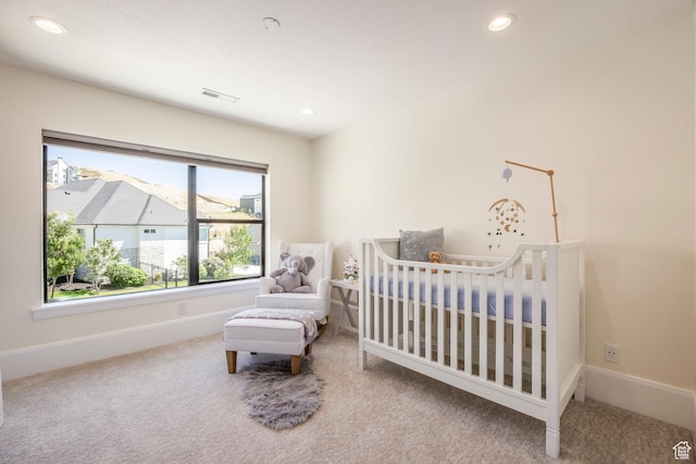 carpeted bedroom featuring a nursery area