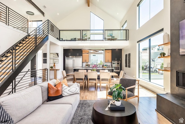 living room featuring beam ceiling, high vaulted ceiling, and light hardwood / wood-style floors