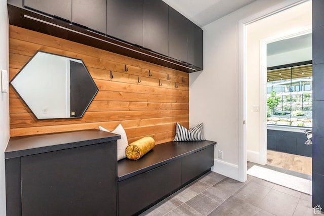 mudroom featuring tile patterned floors and wood walls