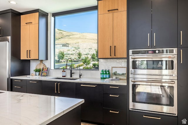 kitchen with a wealth of natural light, light stone counters, sink, and stainless steel double oven