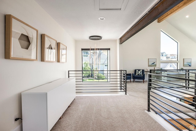 corridor with vaulted ceiling with beams and light colored carpet