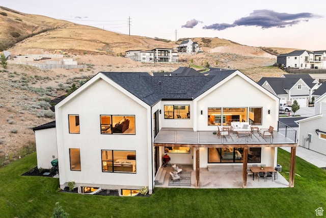 rear view of house with a lawn, a mountain view, a patio area, and a balcony