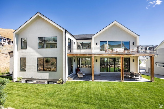 rear view of house featuring a patio area, a yard, and a balcony