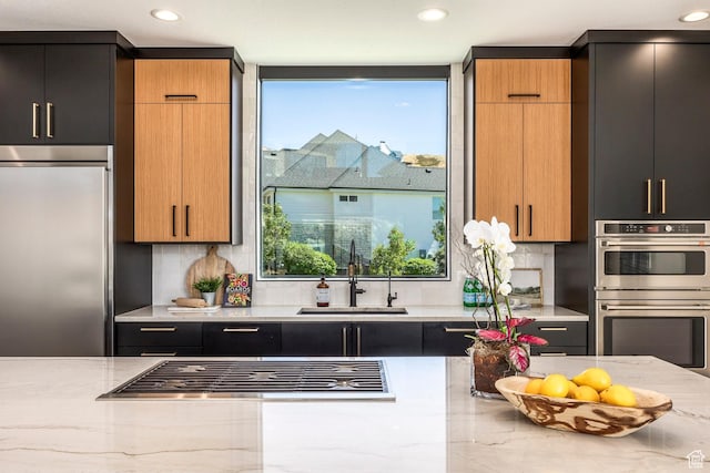 kitchen featuring decorative backsplash, light stone counters, sink, and stainless steel appliances
