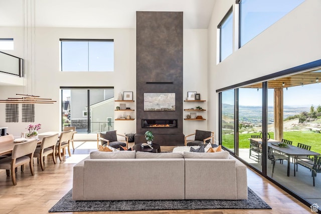 living room featuring a fireplace, a towering ceiling, and light hardwood / wood-style floors