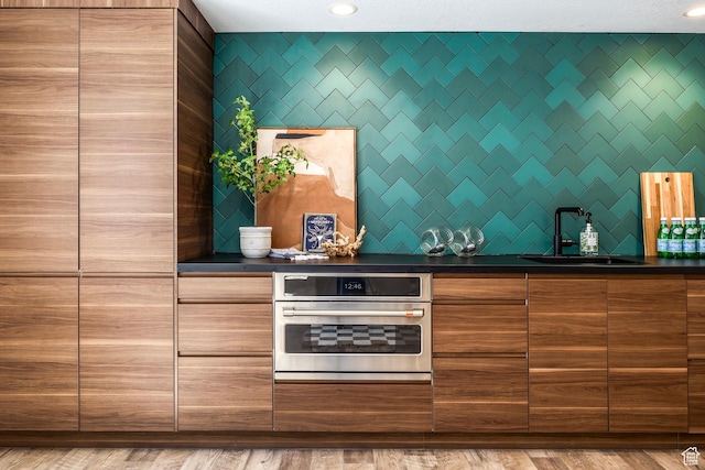 kitchen featuring oven, light hardwood / wood-style floors, and sink