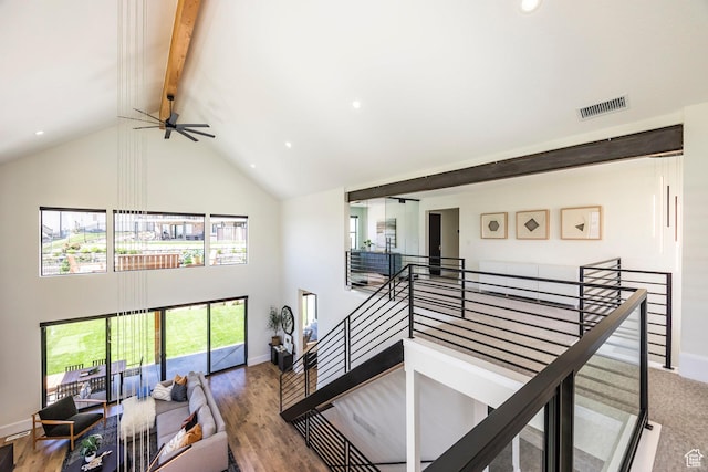 stairs featuring beamed ceiling, ceiling fan, hardwood / wood-style flooring, and high vaulted ceiling